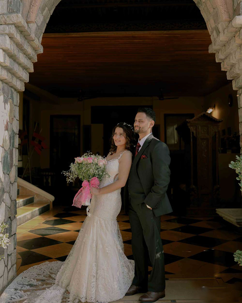 A couple in traditional Indian attire standing in front of an ornate doorway