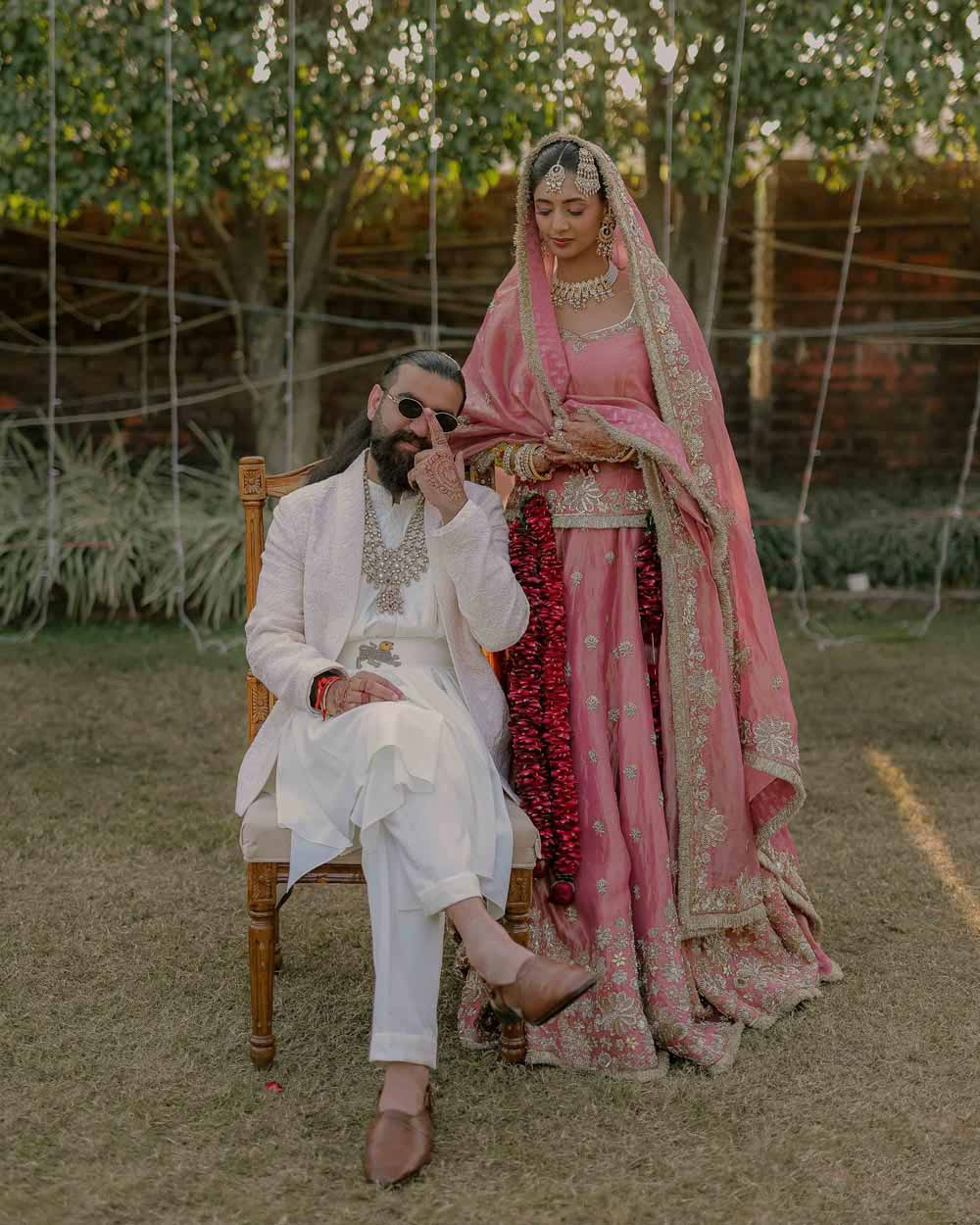 A couple in elegant black outfits standing in a desert landscape at dusk